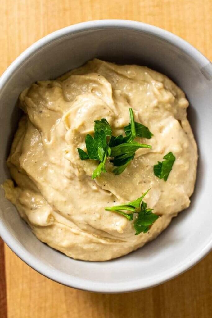 top shot of miso tahini dressing in a small white bowl topped with parsley for garnish