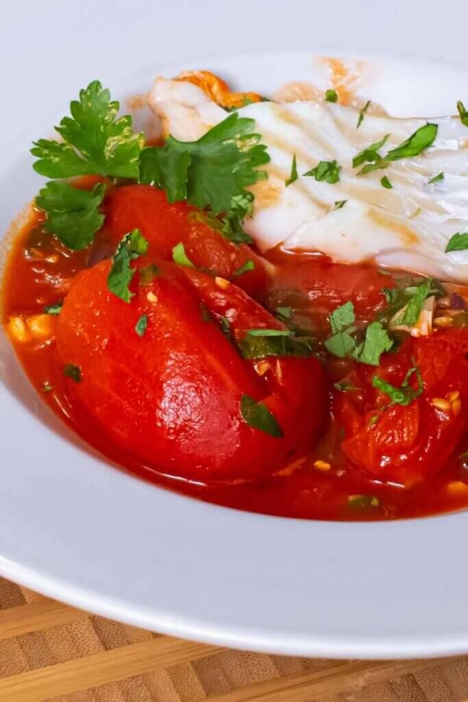 side shot of instant pot cod with puttanesca sauce in a white bowl