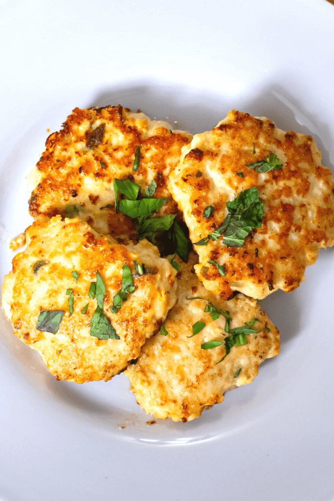 top shot of chicken breakfast sausage patties topped with a garnish on a white plate