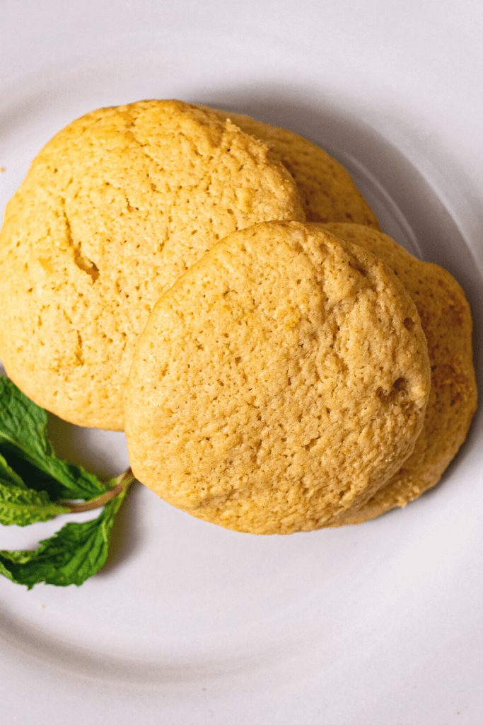 top view of olive oil cookies next to green garnish on white plate