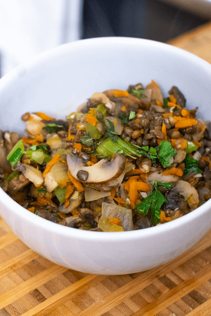 lentil mushroom stew with veggies in a white bowl 