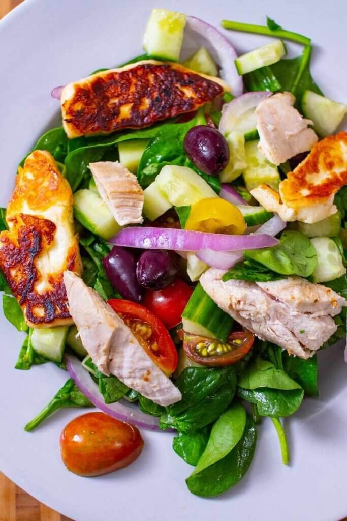 chicken and halloumi salad in a bowl with spinach and veggies
