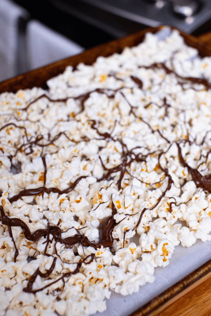 top shot of chocolate drizzled popcorn on a baking sheet