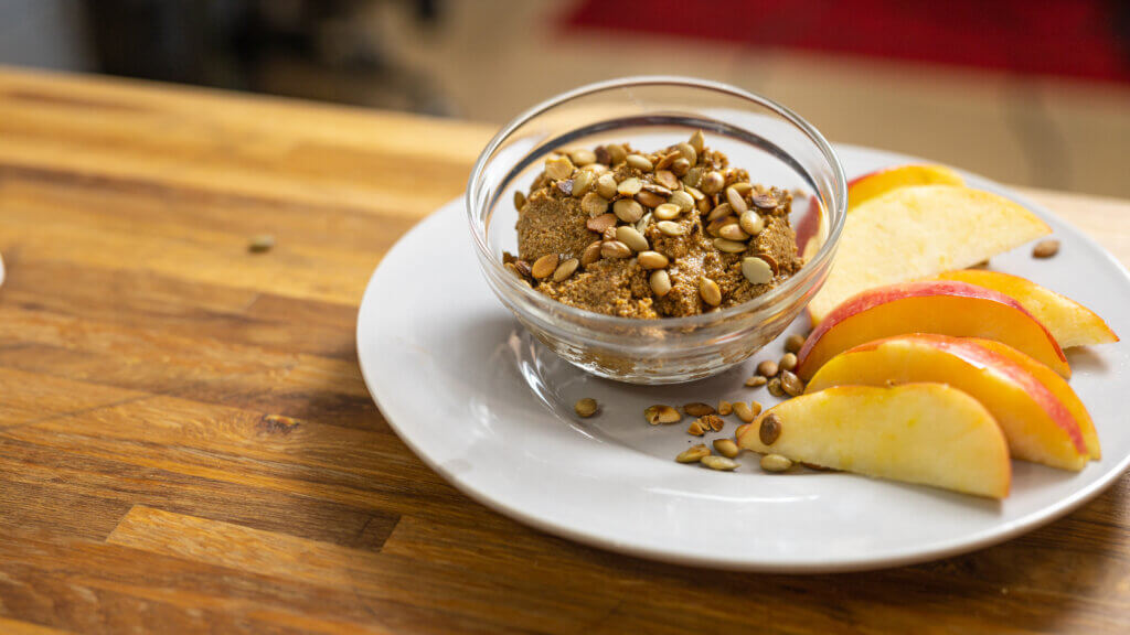 pumpkin seed butter in glass bowl next to sliced apples