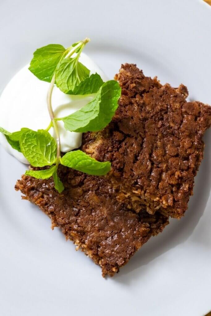 top view of chocolate baked oats next to yogurt and garnish on white plate