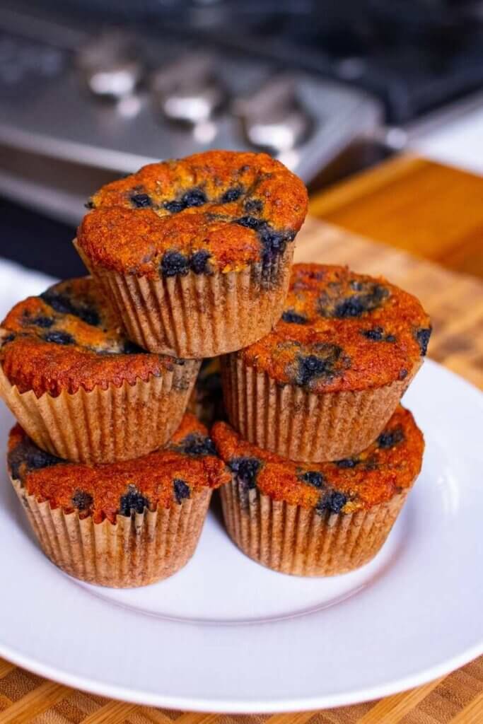 5 blueberry chia muffins stacked on a white plate