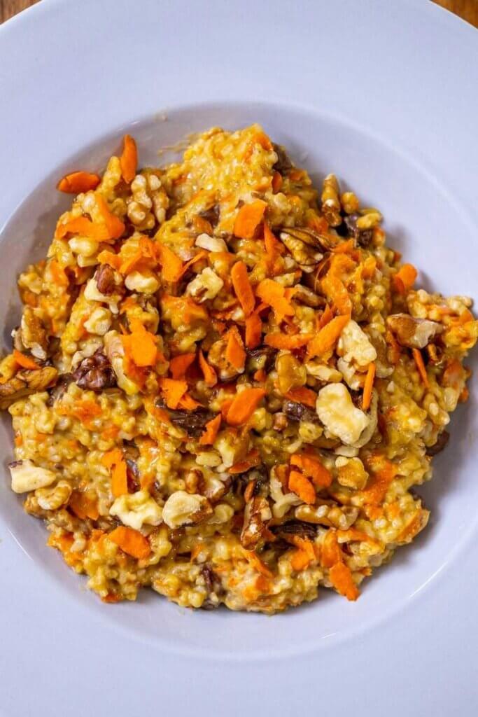 carrot cake oatmeal with walnuts and raisins in a large white bowl