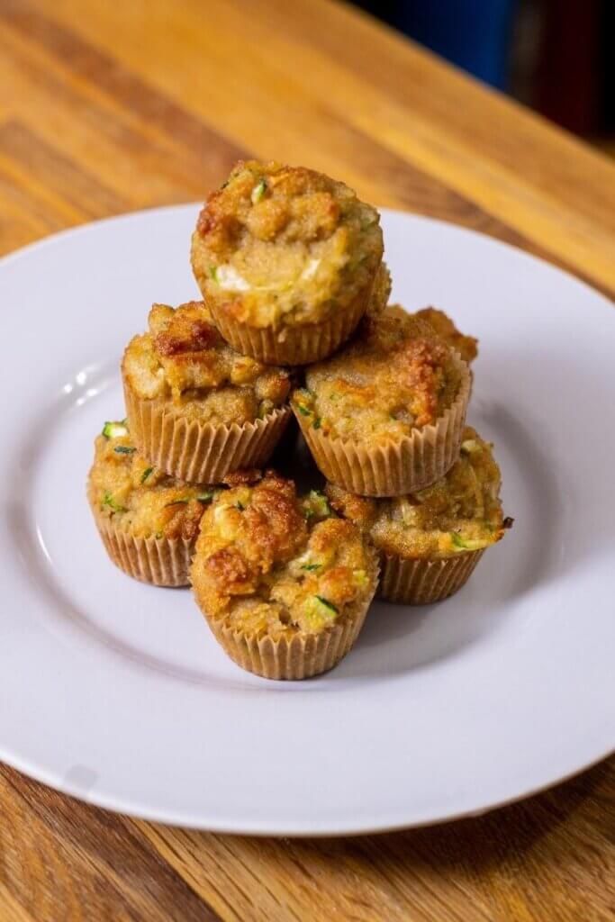 a stack of almond flour zucchini muffins on a white plate