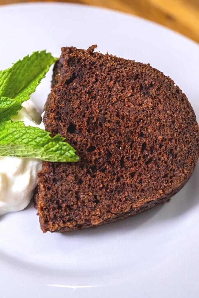 slice of chocolate orange cake on a white plate next to greek yogurt