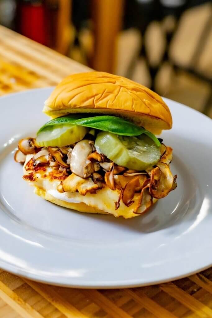 mushroom halloumi burger on a bun on a white plate