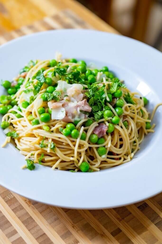 a large bowl of pasta with green peas