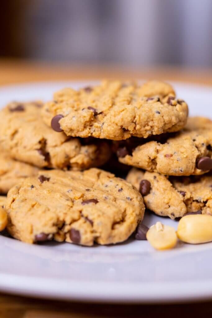 side view of vegan peanut butter chocolate chip cookies on a white plate