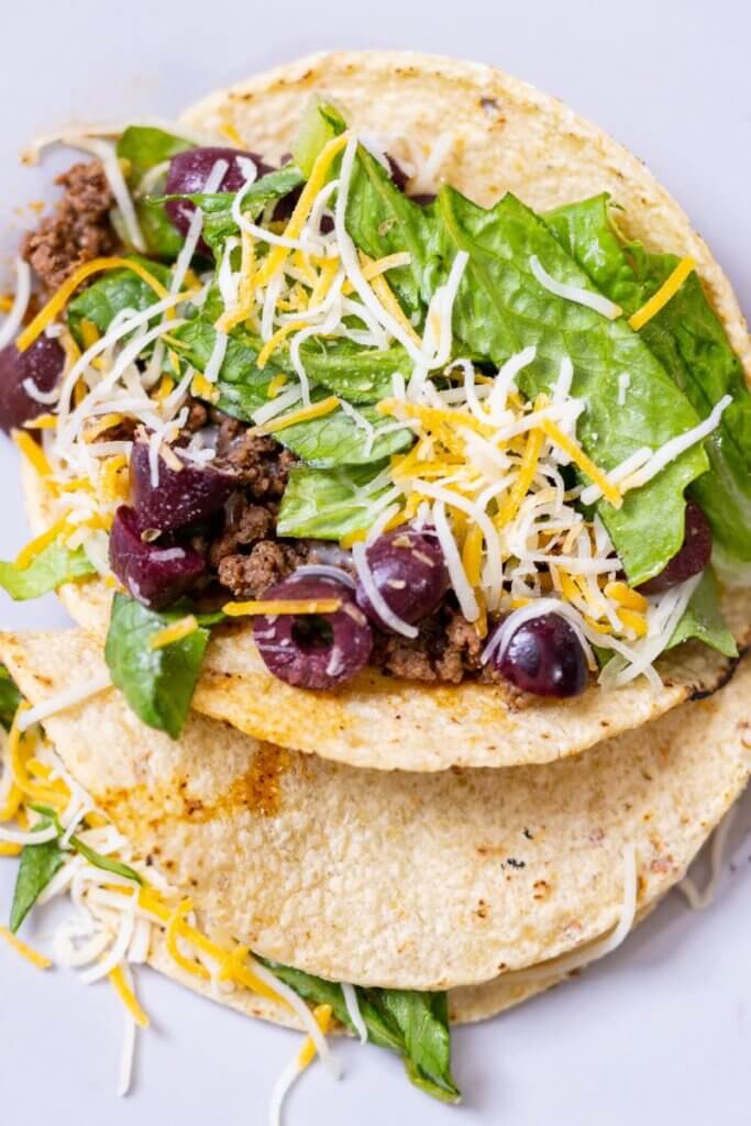 top view of low FODMAP tacos with olives on a white plate