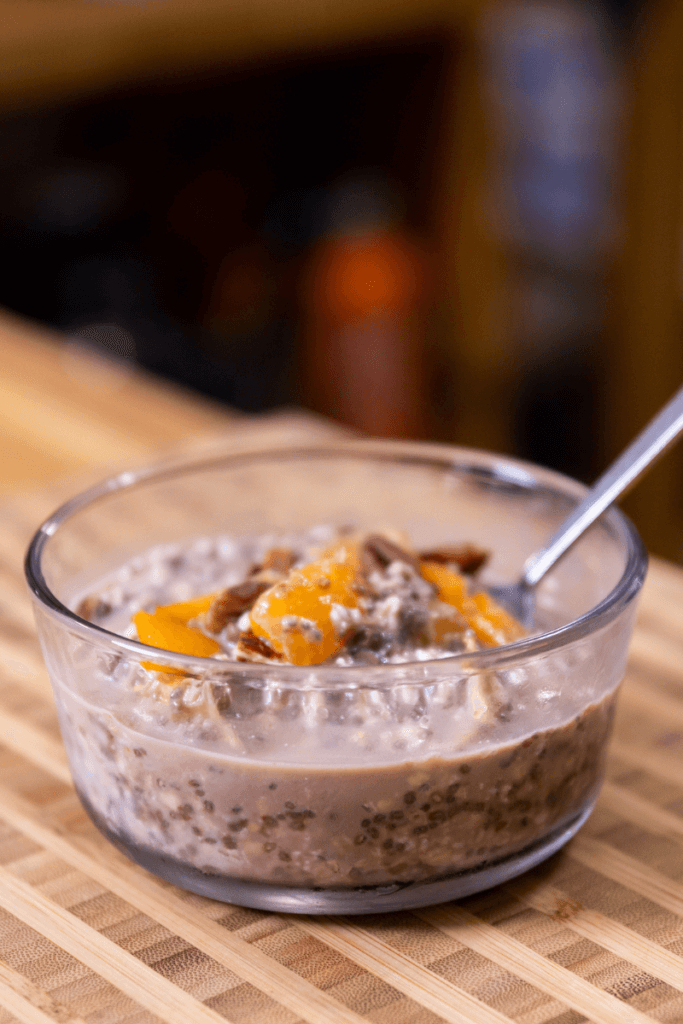 side view of chocolate orange overnight oats in a glass bowl with a spoon