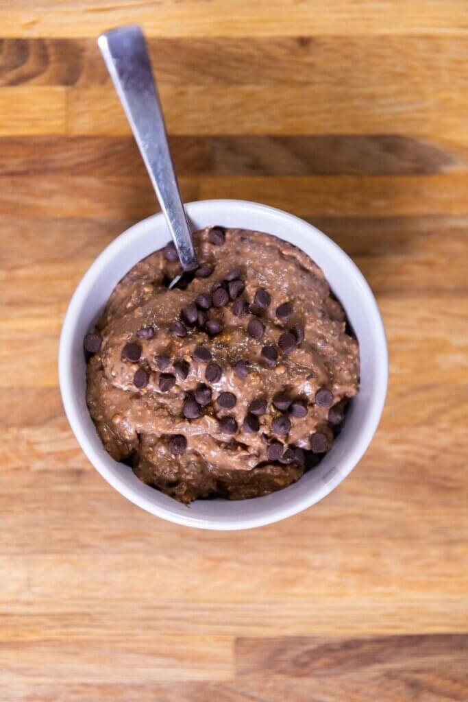 top view of edible brownie batter topped with chocolate chips with a spoon