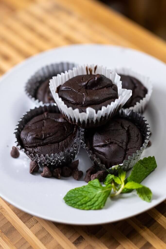 side view of black bean brownies in muffin wrappers stacked on a plate