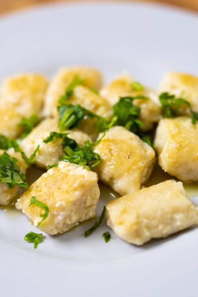 tofu gnocchi on a white plate garnished with parsley.