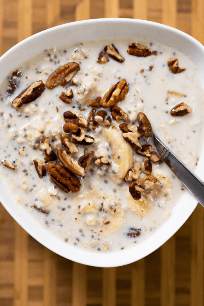 top view of a white bowl filled with tahini overnight oats, topped with bananas and pecans.
