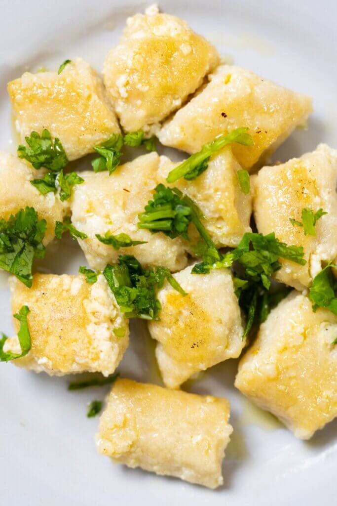 top of tofu gnocchi on a white plate sprinkled with parsley.