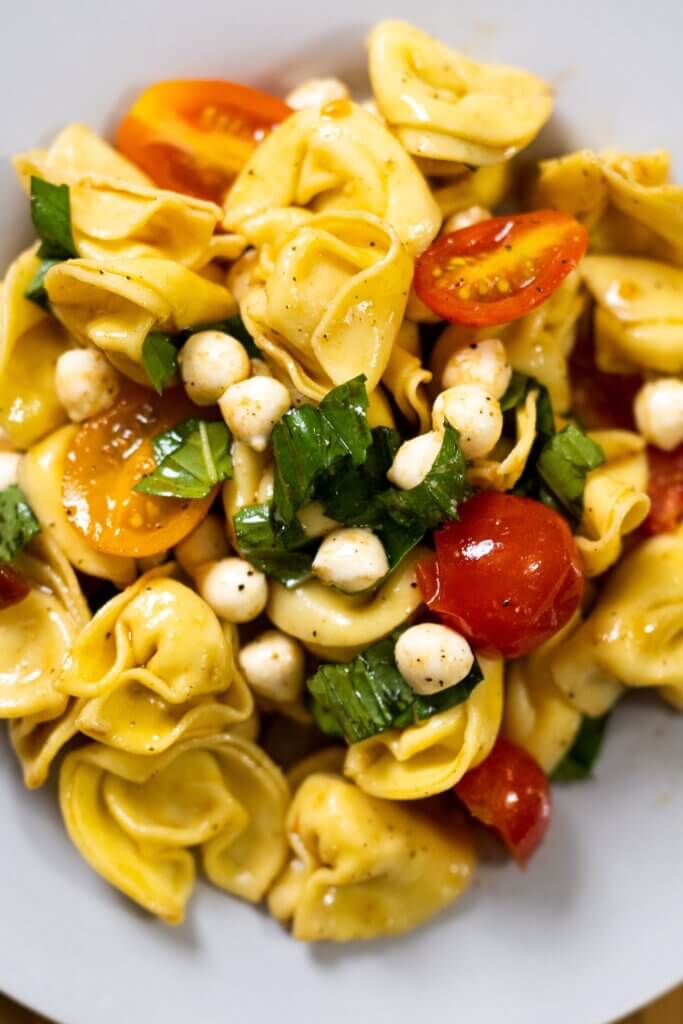 top view of tortellini caprese salad on a white plate