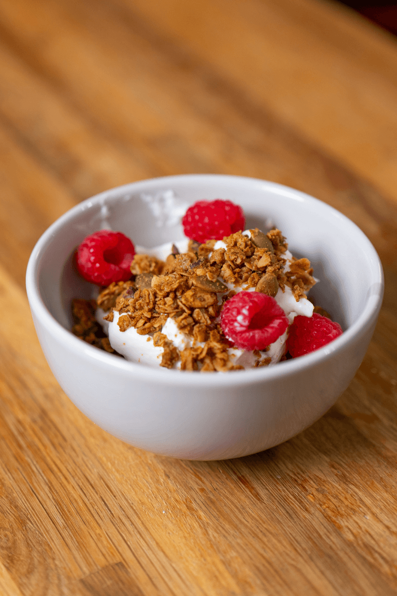 peanut butter granola in a bowl with yogurt and raspberries.