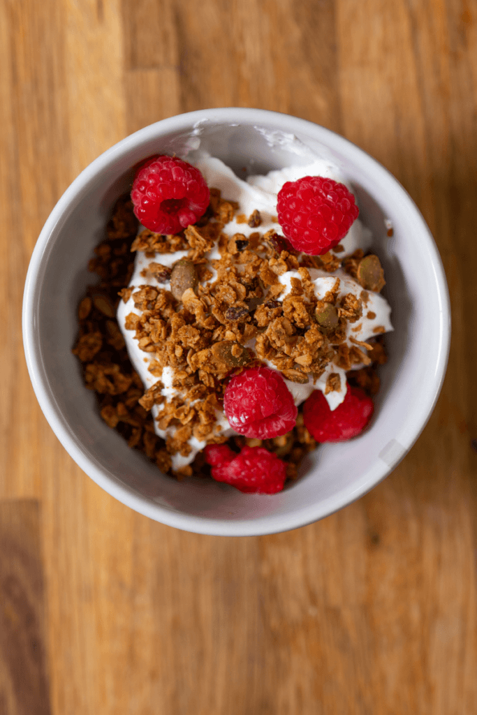 top view of a yogurt bowl with homemade peanut butter granola and raspberries. 