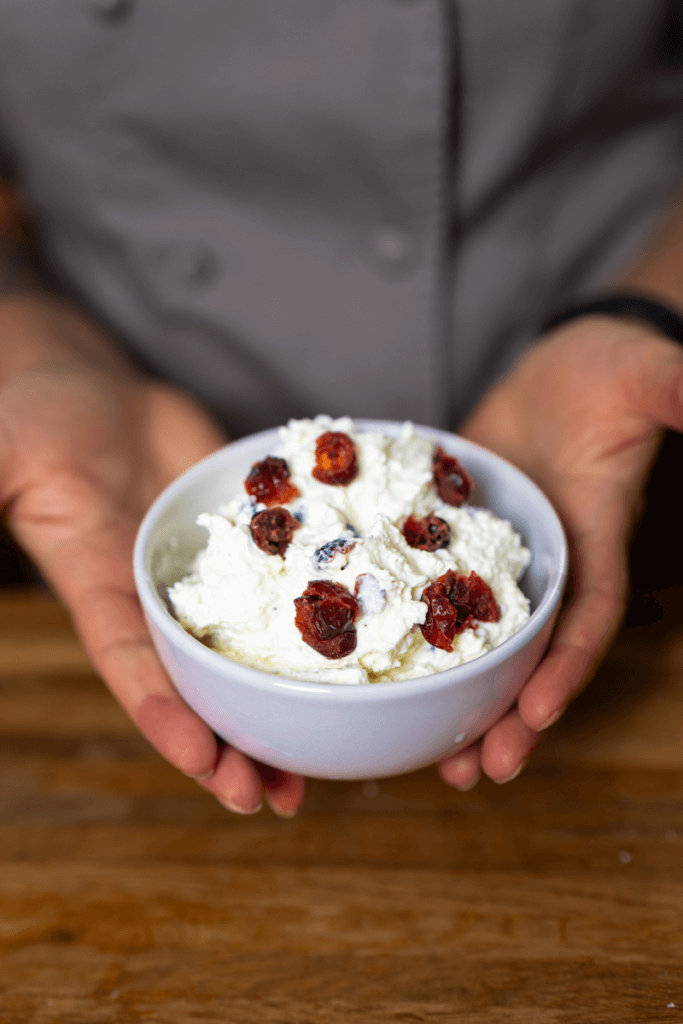 holding a small bowl of whipped cranberry feta dip.