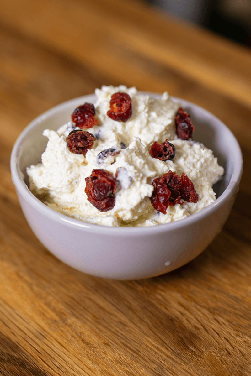 Cranberry whipped feta cheese dip in a white bowl topped with dried cranberries.