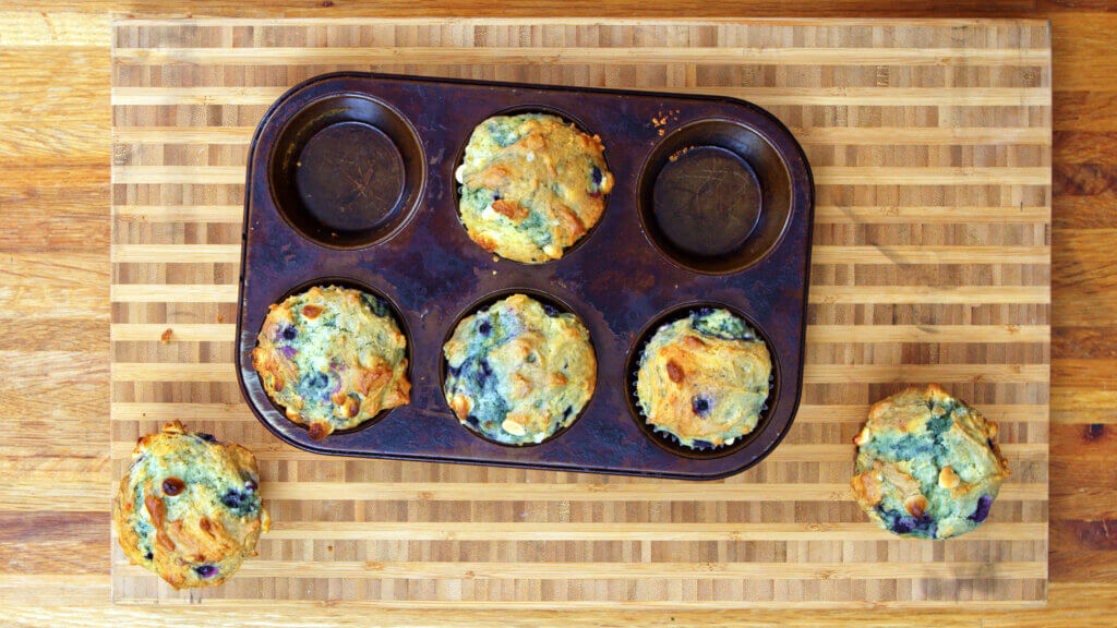 Top view of blueberry white chocolate muffins on a cutting board.