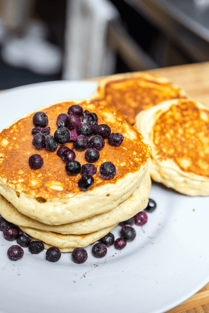 A stack of lentil pancakes on a white plate topped with blueberries.