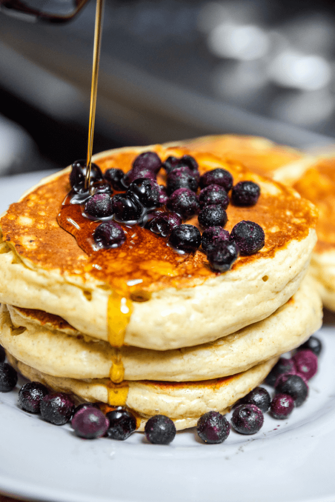 Drizzling syrup over a stack of lentil pancakes.