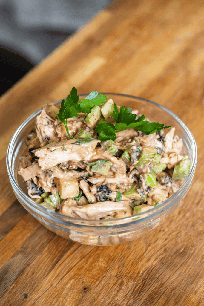 A large glass bowl of homemade chicken salad with cherries.