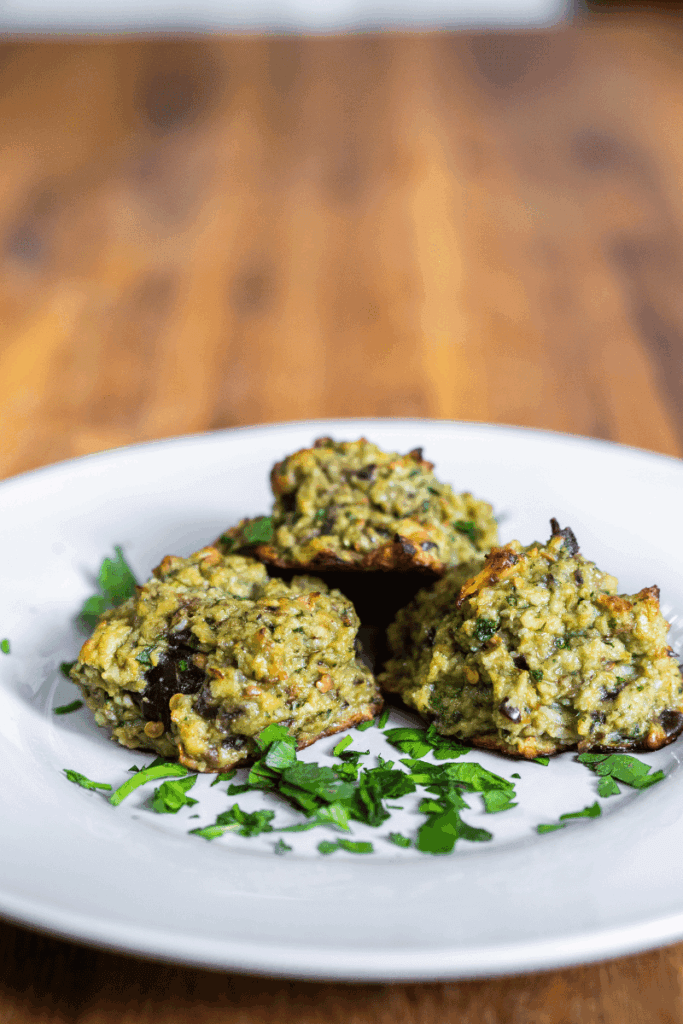 Close up of eggplant parm meatballs on a white plate.