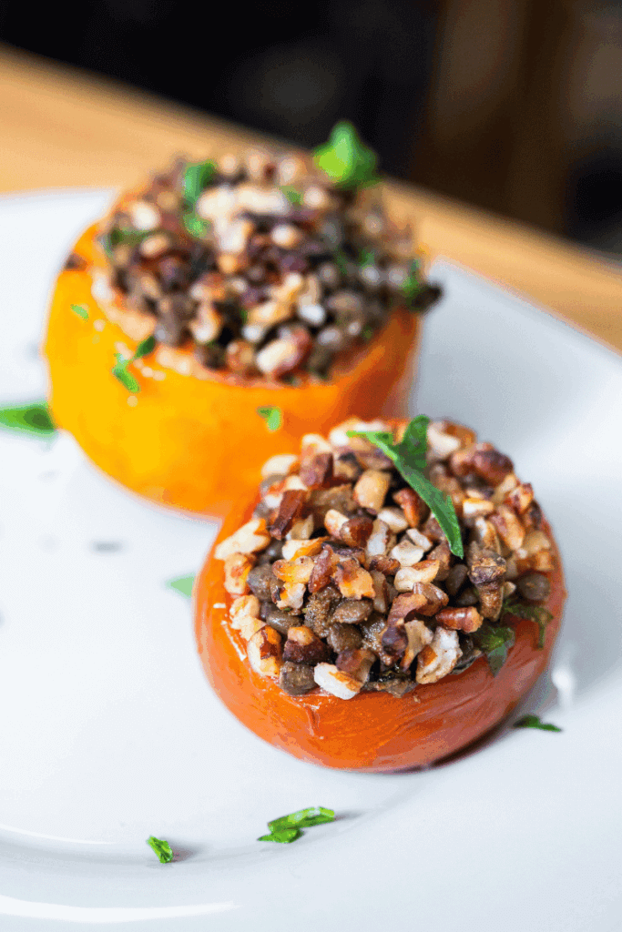 Top view of vegan stuffed tomatoes on a white plate garnished with parsley.